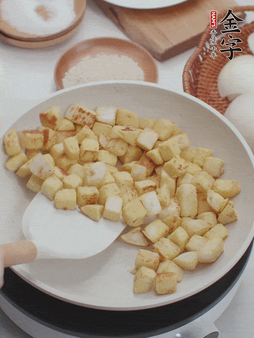 起鍋熱油，倒入饅頭丁，小火煎至蛋液凝固定型再翻面，饅頭丁部煎至金黃時盛起待用。
