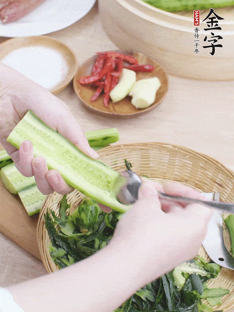 黃瓜削皮，對半切開，勺子挖去內(nèi)瓤，斜刀切片。青蒜斜刀切段。