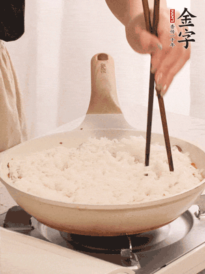 把瀝干水分的米飯均勻鋪在上面，筷子戳幾個(gè)洞，以便透氣，轉(zhuǎn)小火蓋上蓋子燜至水分收干，大概10分鐘。